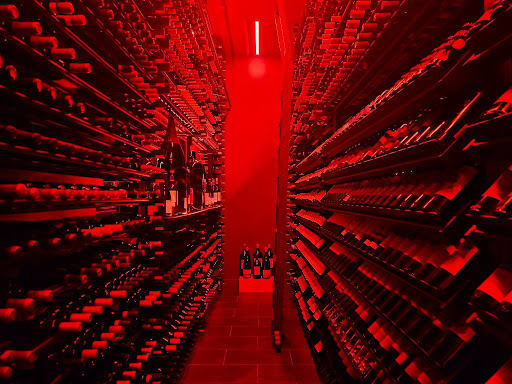 A wine cellar with bottles along the wallis shown in a red light.