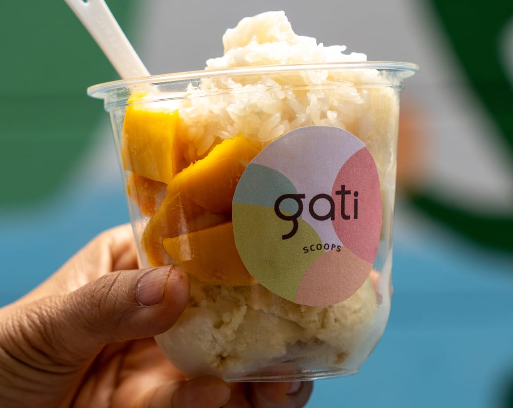 A clear cup that has mangos and ice cream in it. The cup says "gati."
