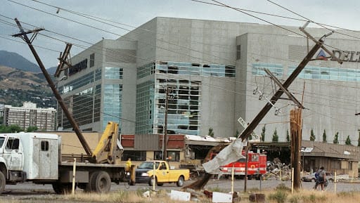 Tornado damage in Salt Lake City shows shattered windows at the Delta Center and downed power lines. 