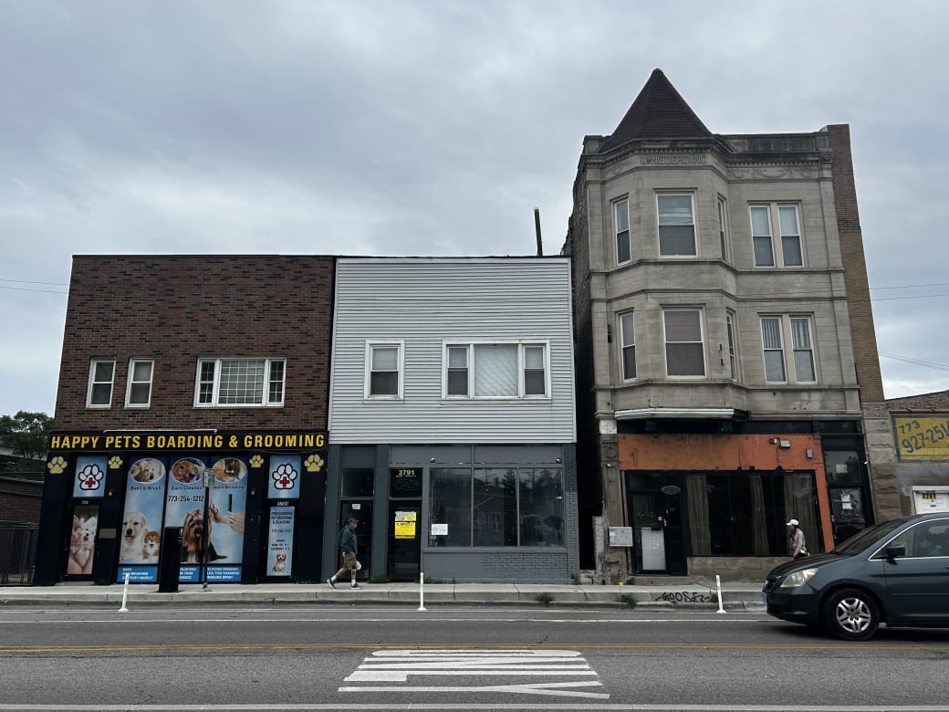 Three buildings lined up next to eachother. The one on the left says "Happy Pets Boarding & Grooming" The other two seem to be abandoned