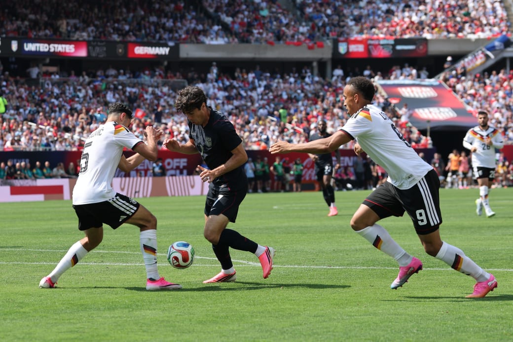 People on a soccer field in a packed stadium playing a game of soccer