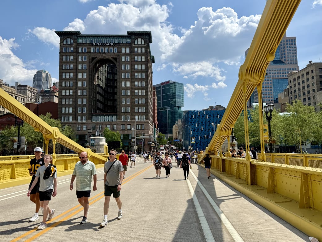 Groups of people walking along a yellow bridge in downtown pittsburgh