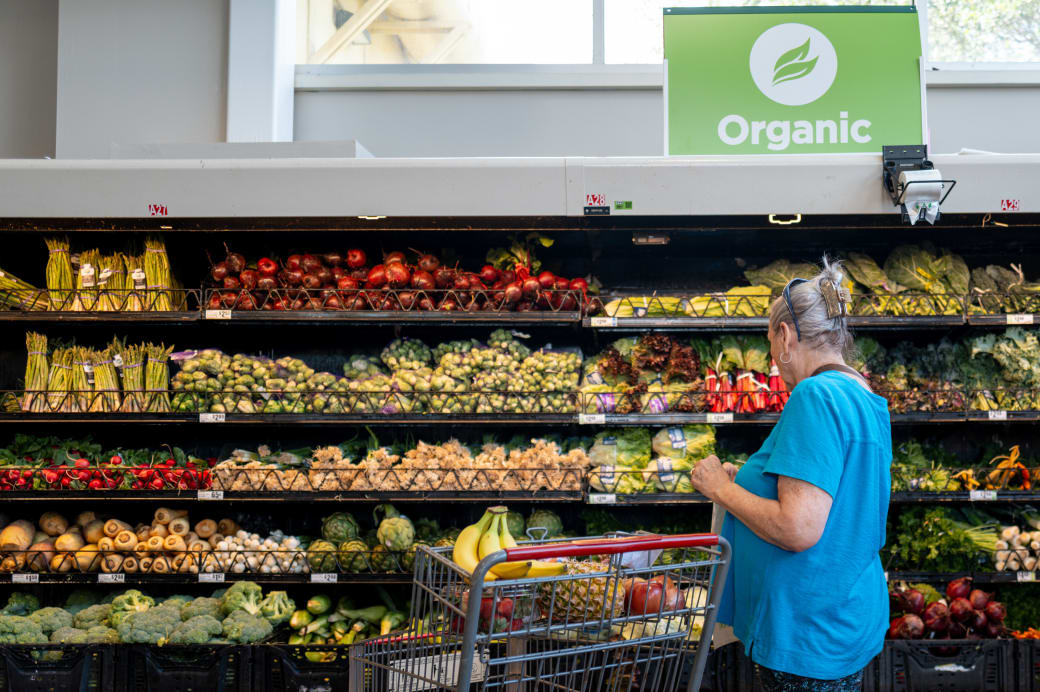 A person grocery shopping in the vegetable section.