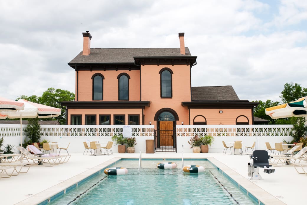 A pool behind an orange two-story house.