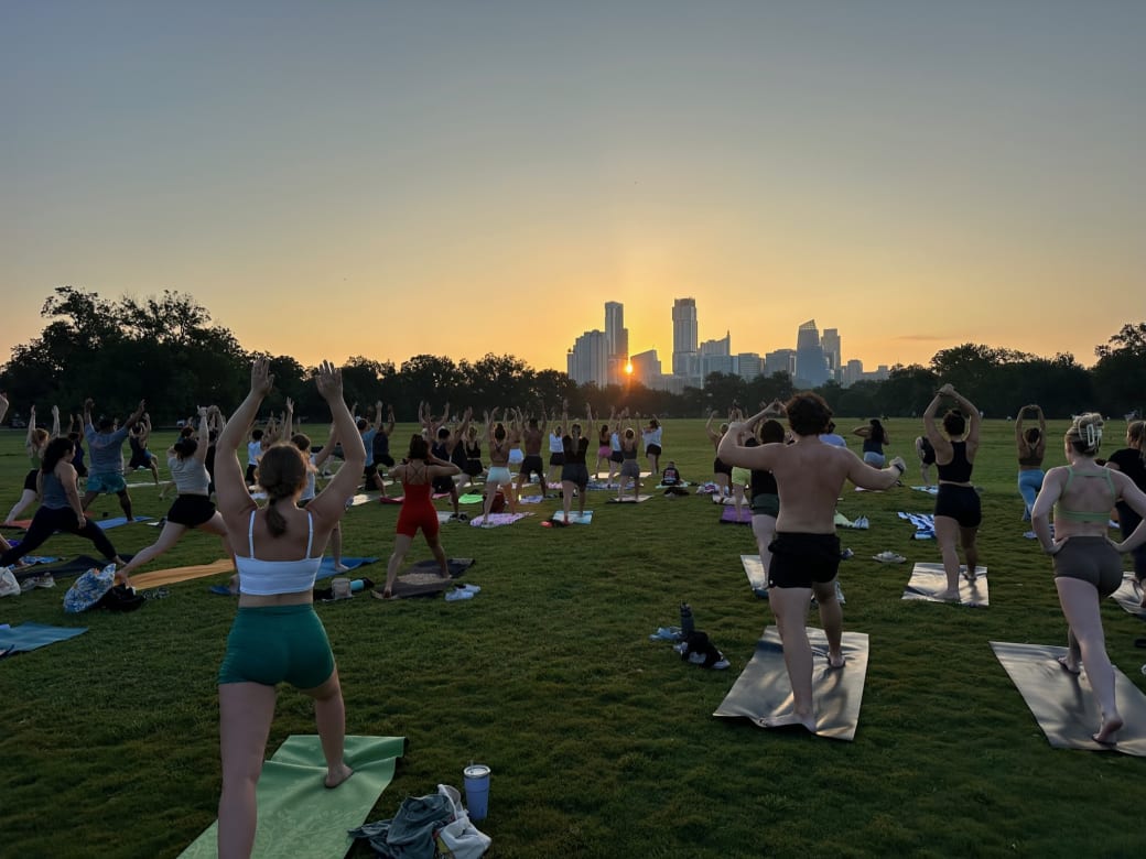 People doing yoga at sunrise in a park.