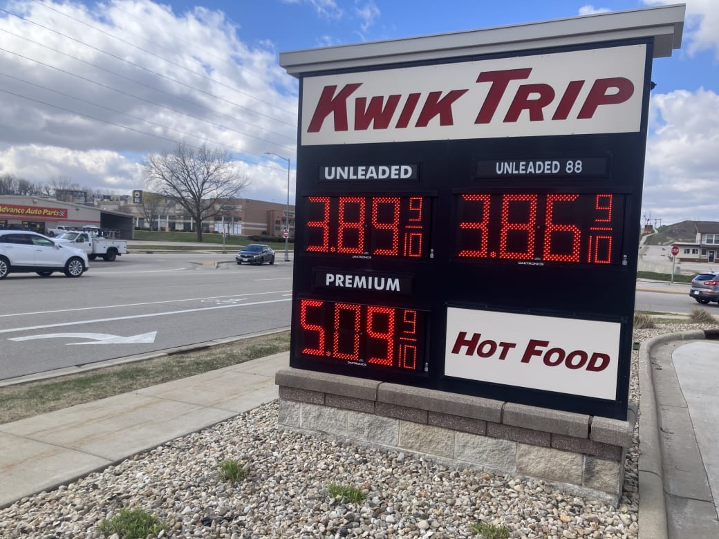 A gas station sign next to a busy road.