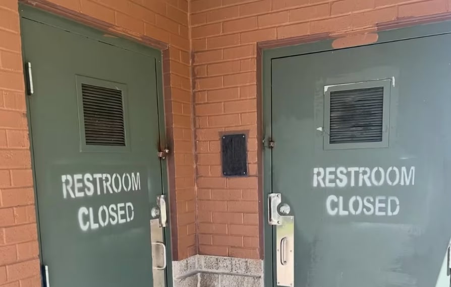 Green doors that say restroom closed in white spray paint.