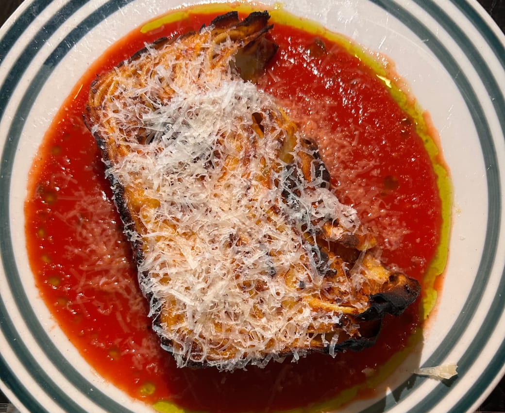 A large piece of lasagna in red sauce with white cheese on top