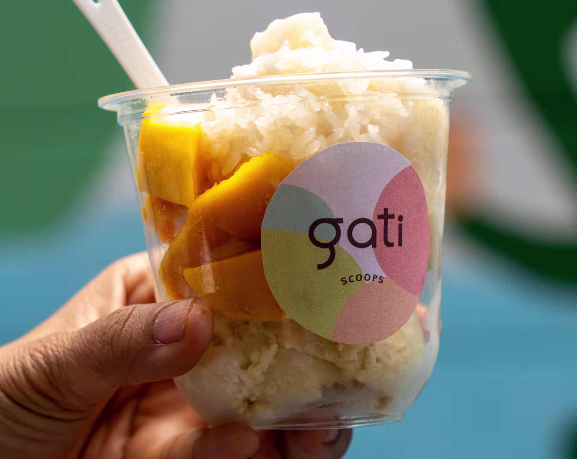 A clear cup that has mangos and ice cream in it. The cup says "gati."