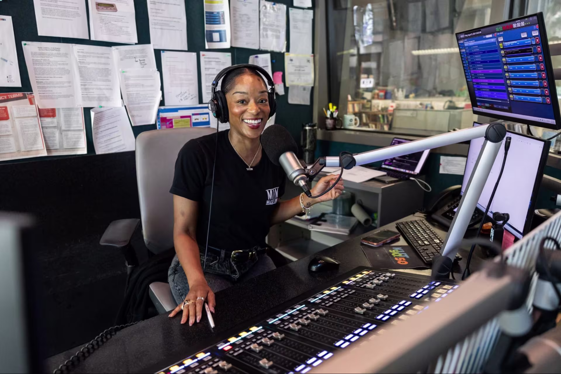 A woman sitting at a microphone in a podcast studio. 