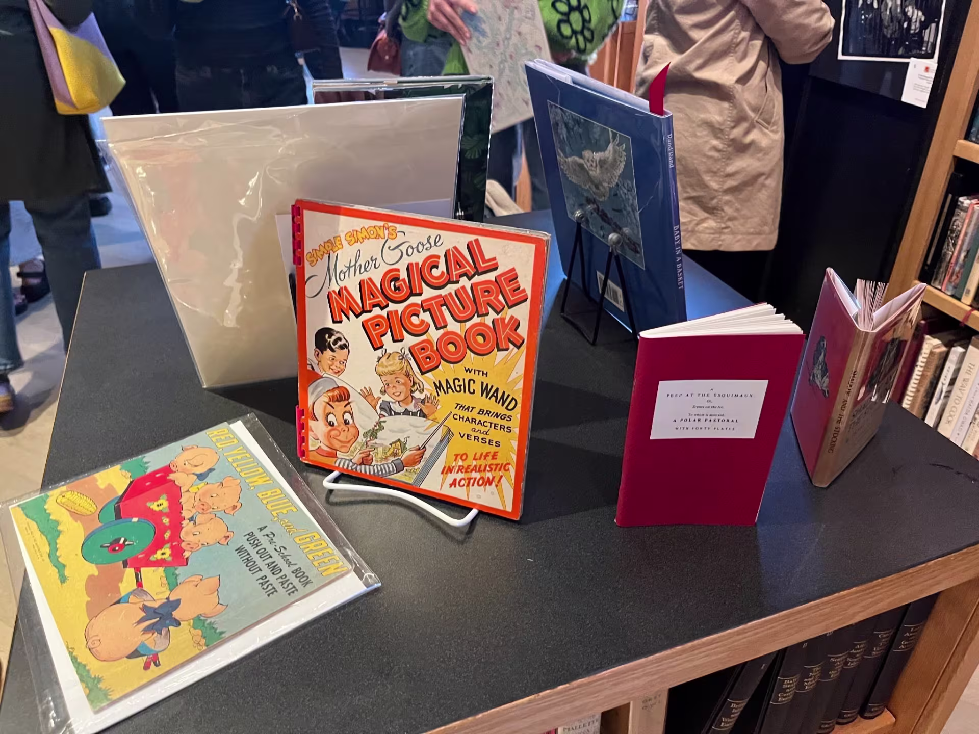 A display table at Long Brothers bookstore in Seattle's Pioneer Square, featuring a curated selection of vintage and rare books including "Simple Simon's Mother Goose Magical Picture Book" and “A Peep at the Esquimaux,” reflecting the shop's eclectic mix of titles.