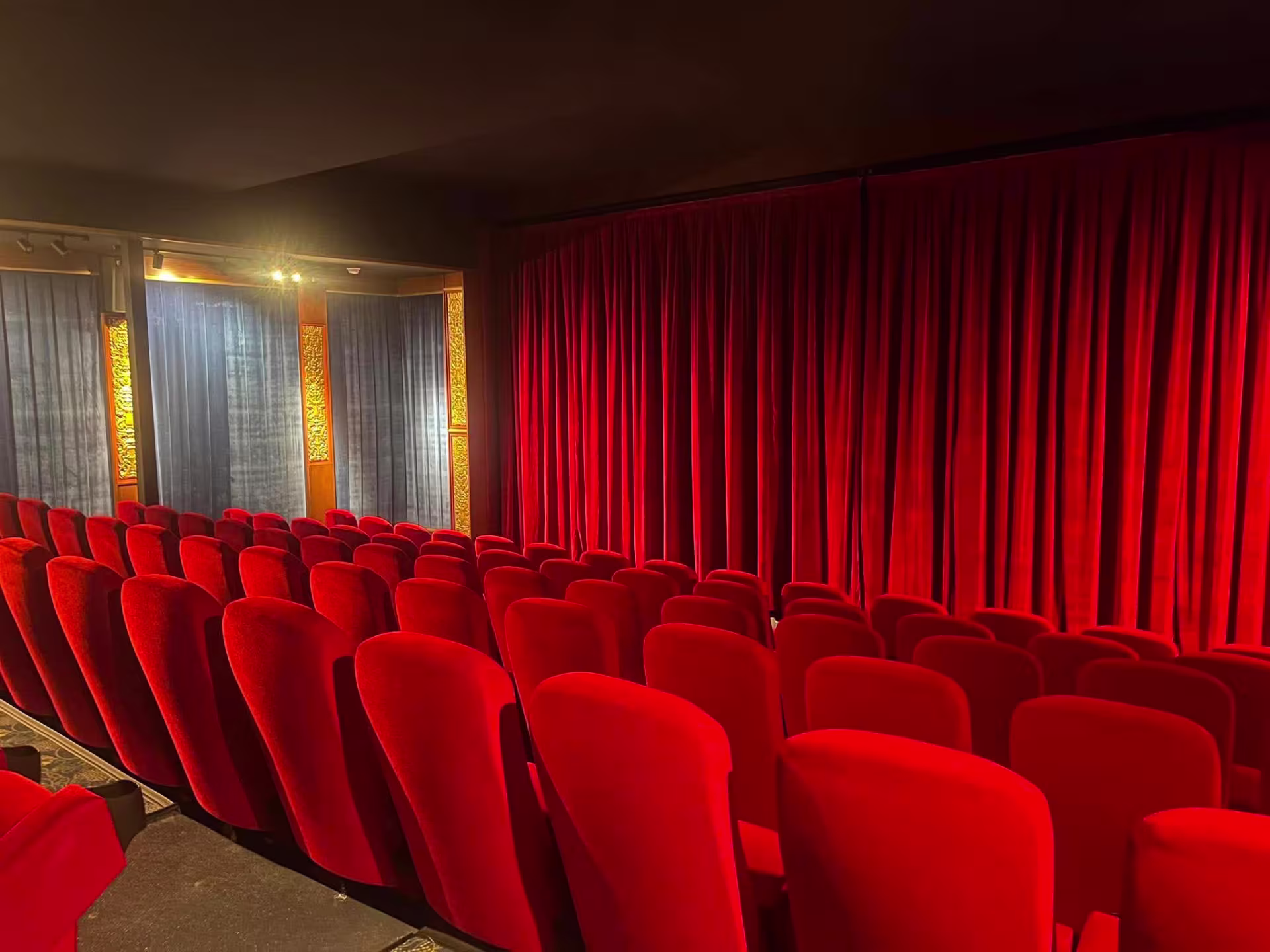 Five rows of plush red velvet seats face a closed red curtain inside the historic Music Box Theatre in Chicago.