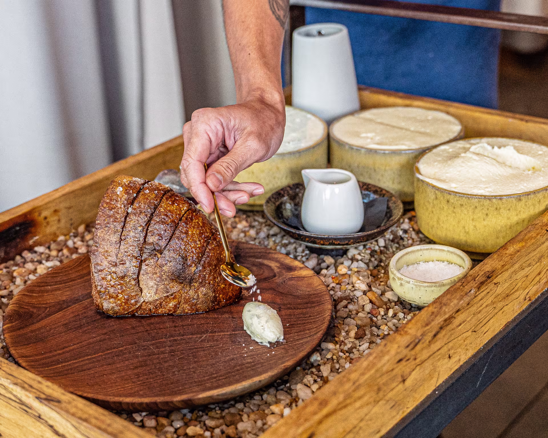 A cart with a loaf of bread and many butters on it. 