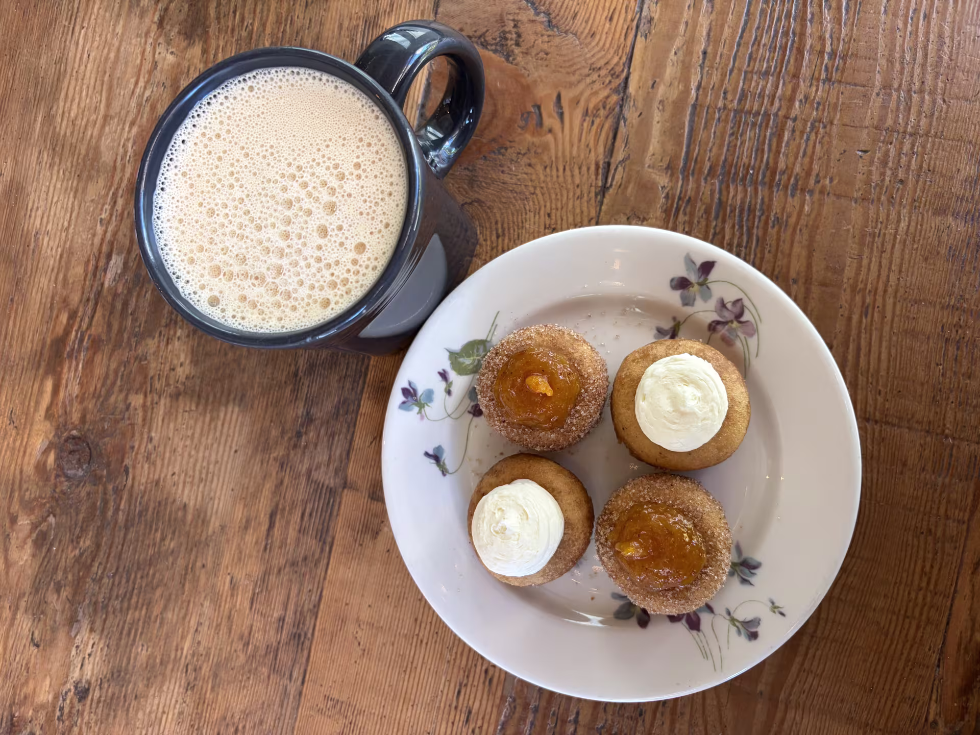 A plate of mini doughnuts and a mug of cider. 