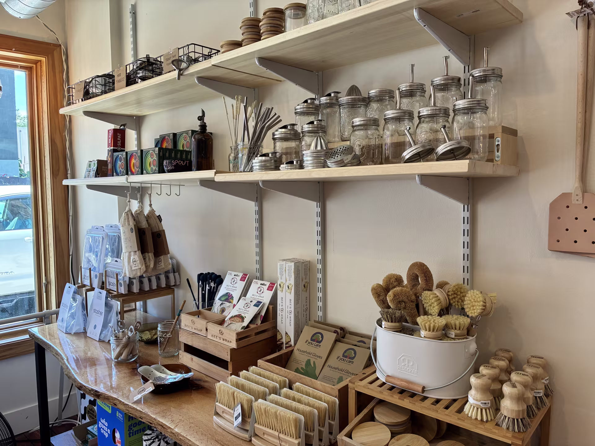 Shelves inside Ray’s Reusables display sustainable products, including empty mason jars, natural scrubbing brushes, bees wrap, stasher reusable bags, chopsticks, metal straws, and laundry bags. 