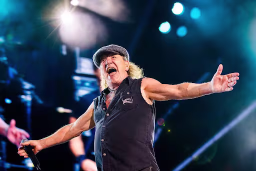 Brian Johnson of AC/DC stands on stage with his arms extended out the side during a concert in Sao Paulo, Brazil