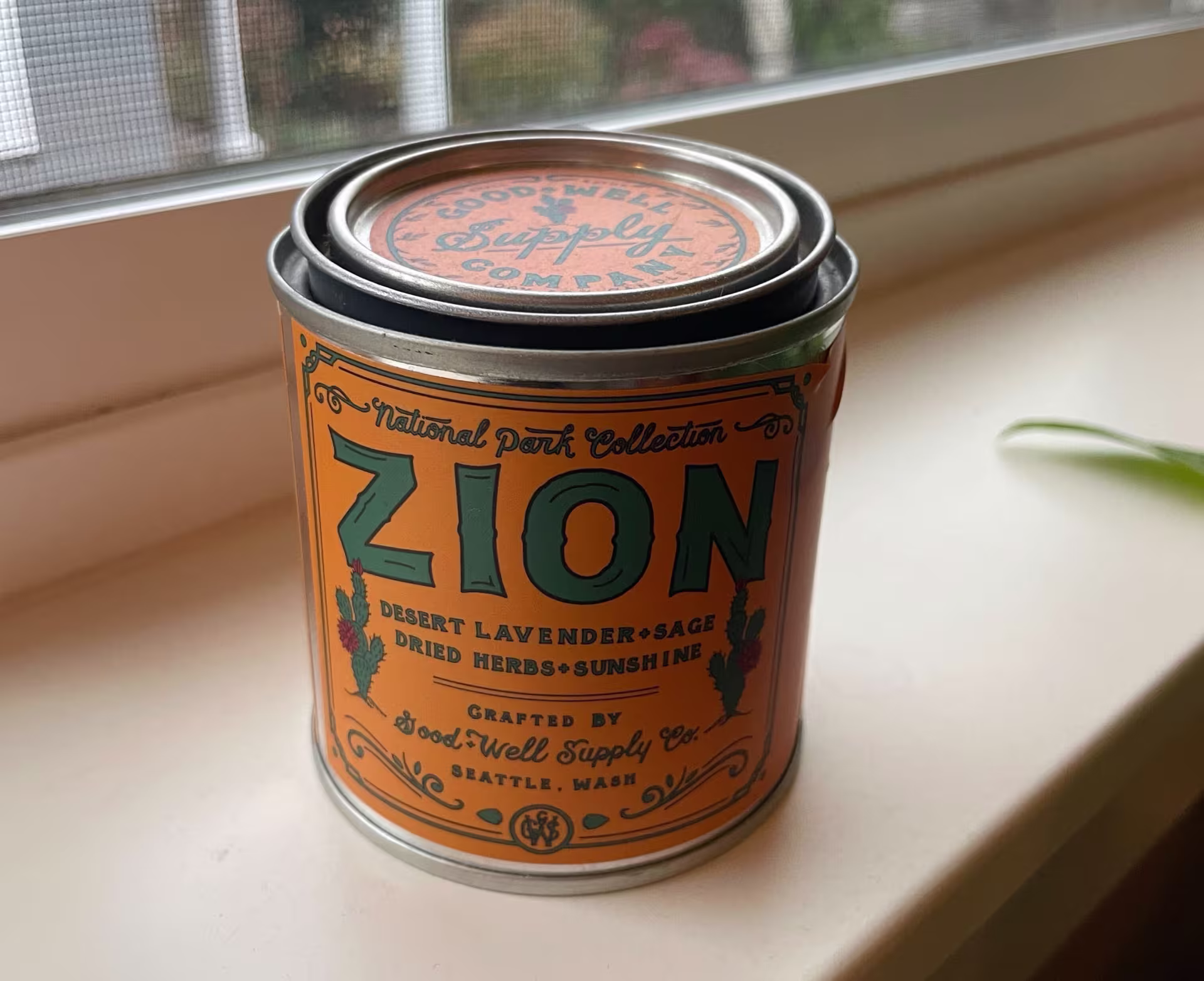 A candle in a tin can with a yellow label. "National Park Collection: ZION"