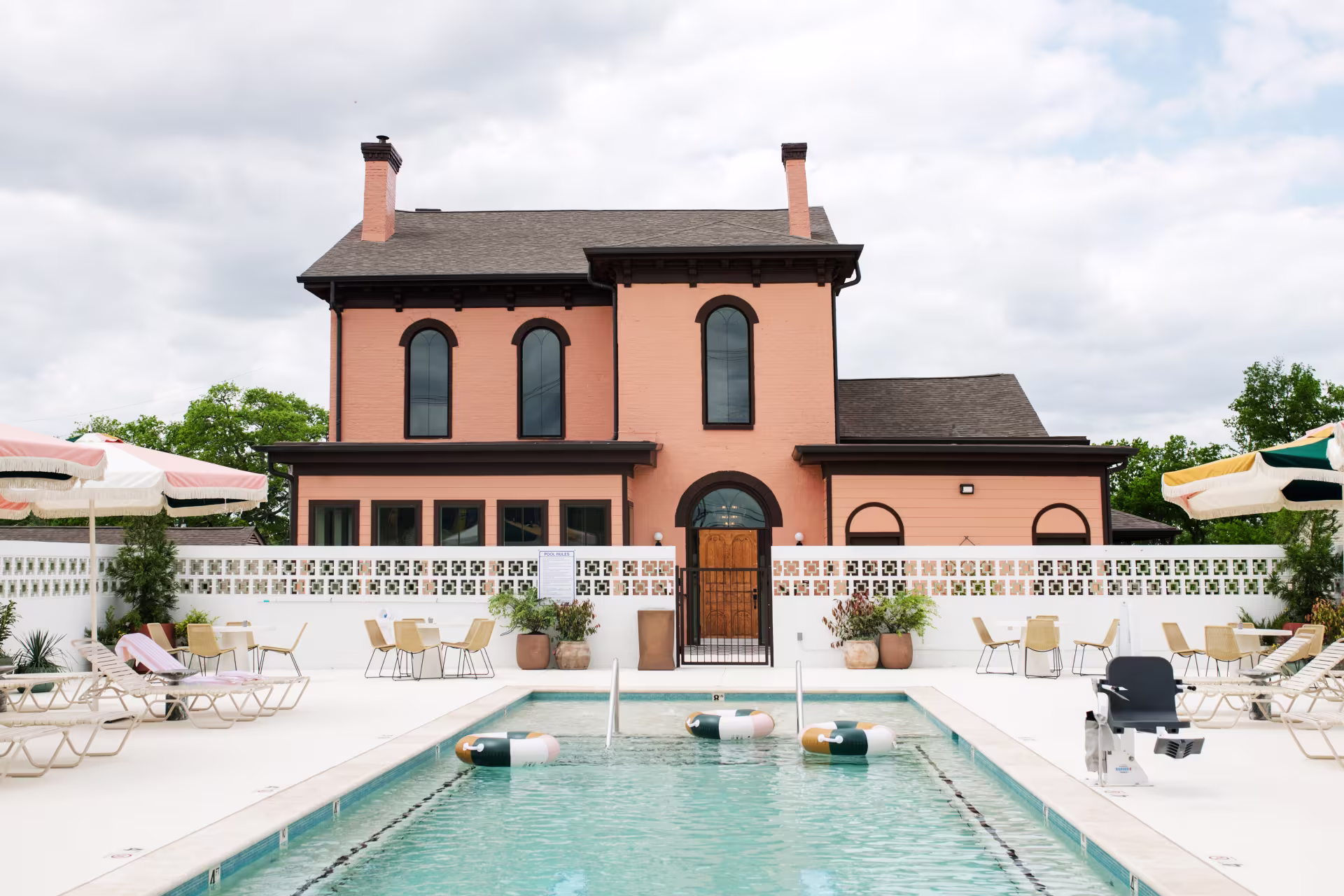 A pool behind an orange two-story house.