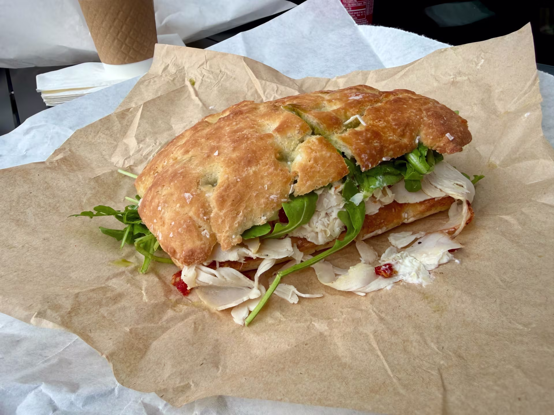 An Italian turkey sandwich on brown parchment paper.