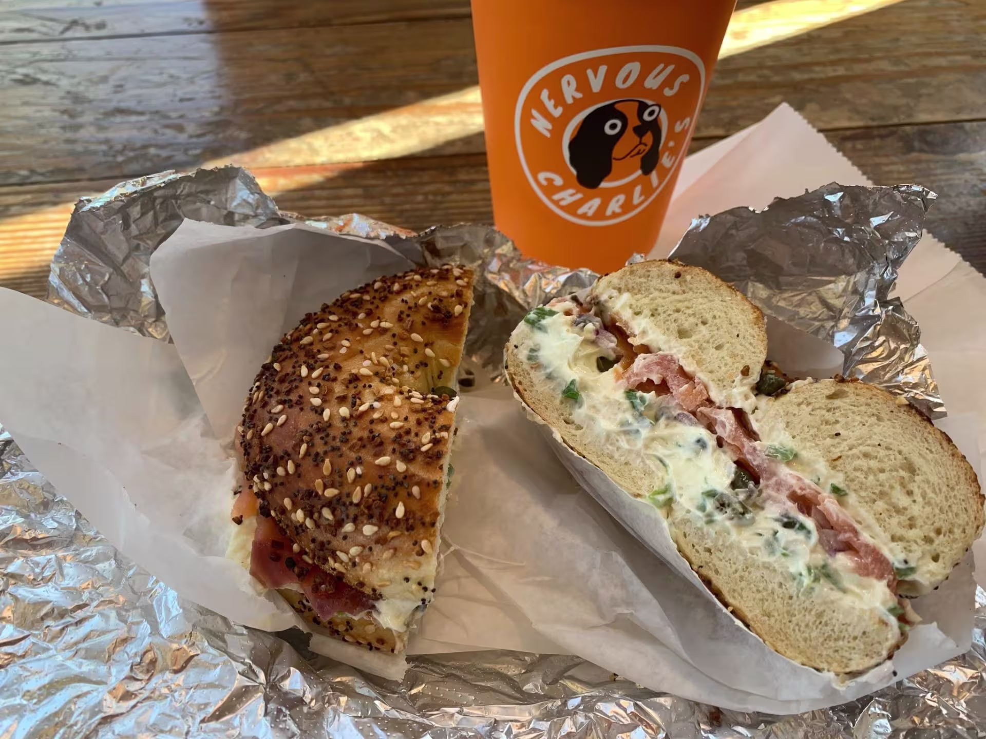 An everything bagel with cream cheese and scallions on foil.