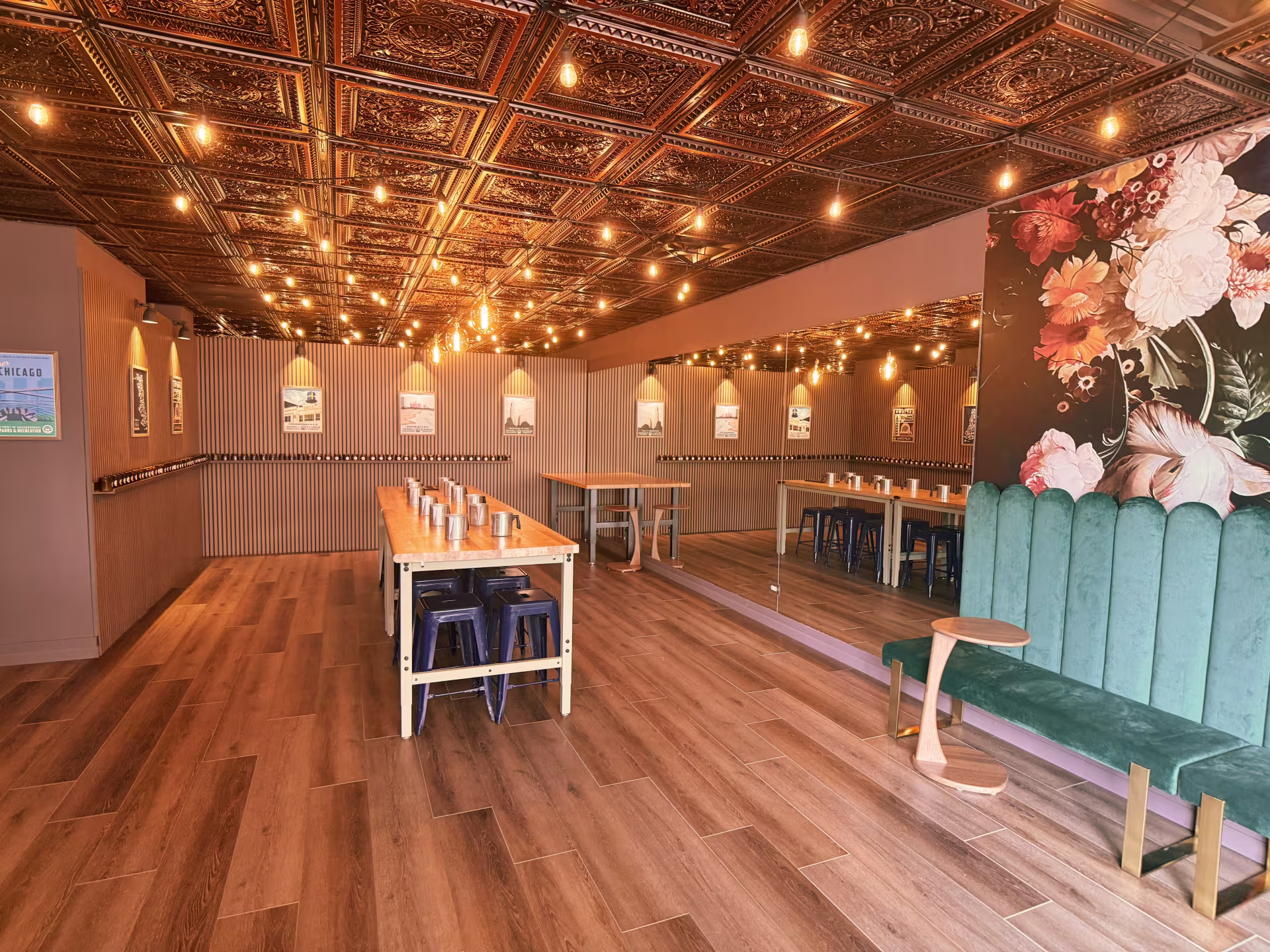 A shop with a lot of lights on the ceiling. The ceiling is also what looks to be intricate golden tile. In the shop, there is a bench to sit along with a table with stools