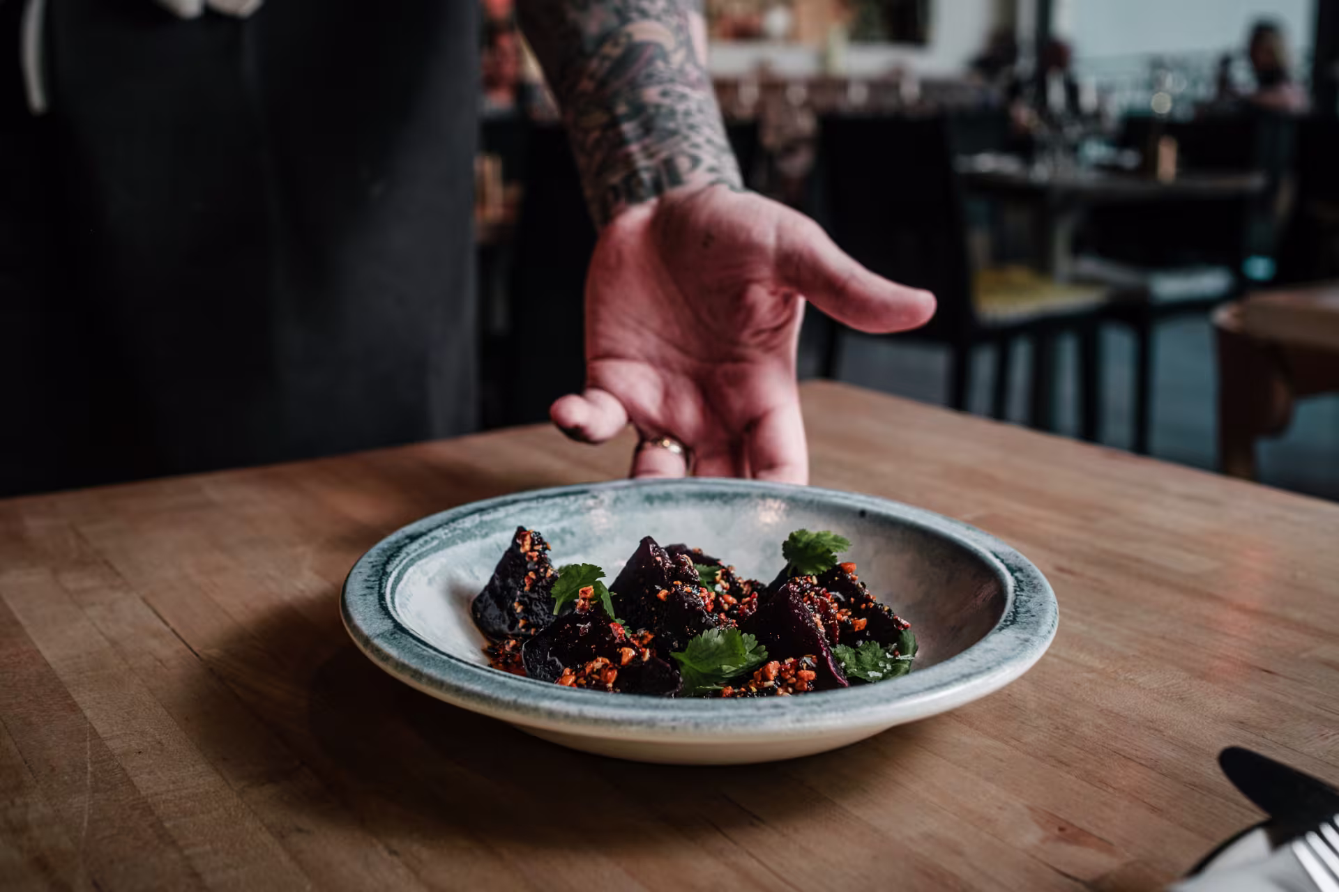 A chef drops a plate of food on a table. 