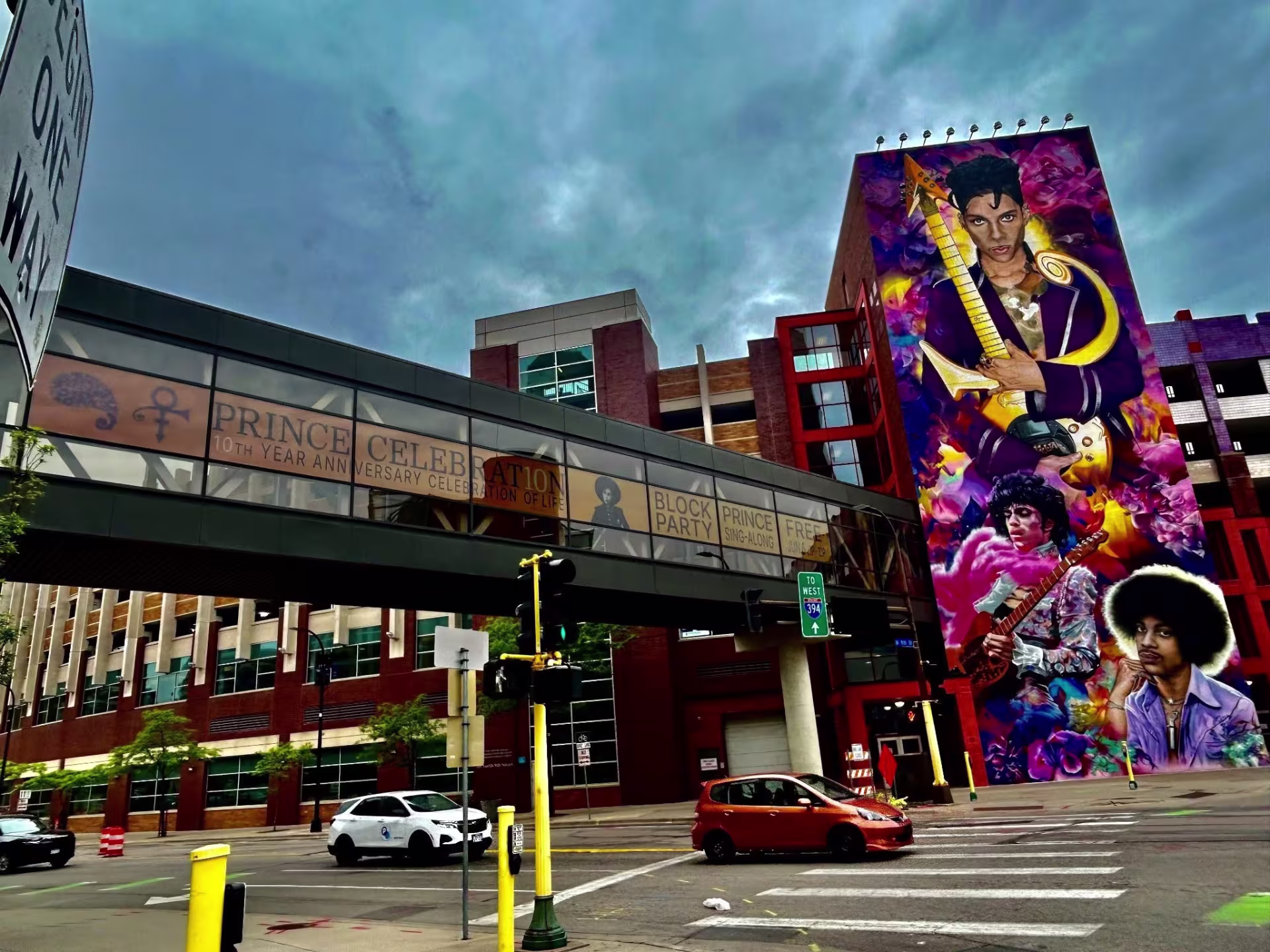 Street-level view of colorful mural featuring musical artist Prince on urban street