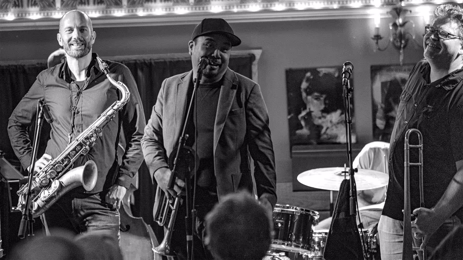 Three horn players smiling on stage.