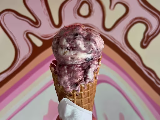 A hand holds an ice cream cone.