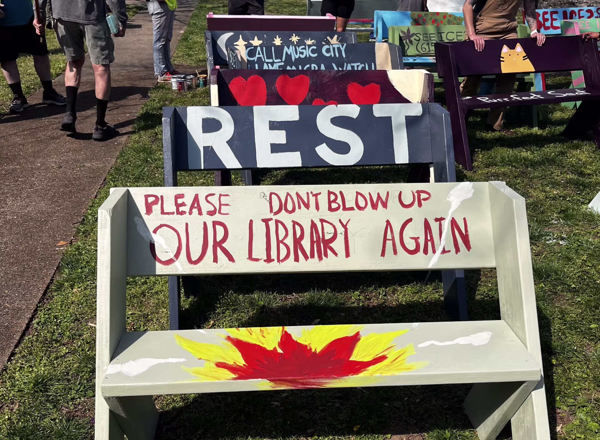 A collection of guerilla benches, painted with different messages like "Rest" 