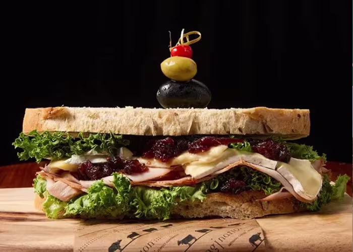A sandwich with turkey and cheese on a wooden table.