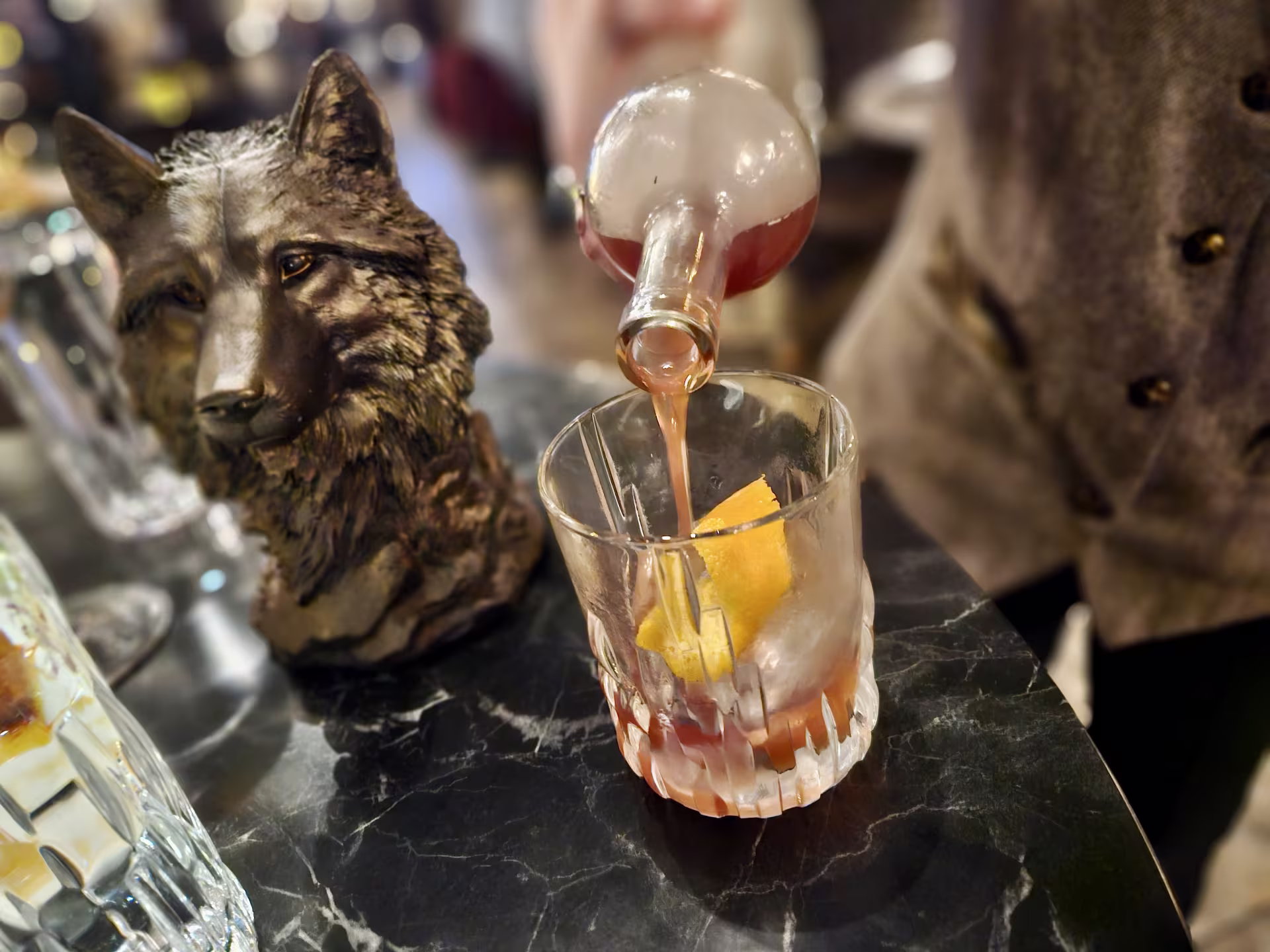 Liquor is poured into a glass behind a bar.