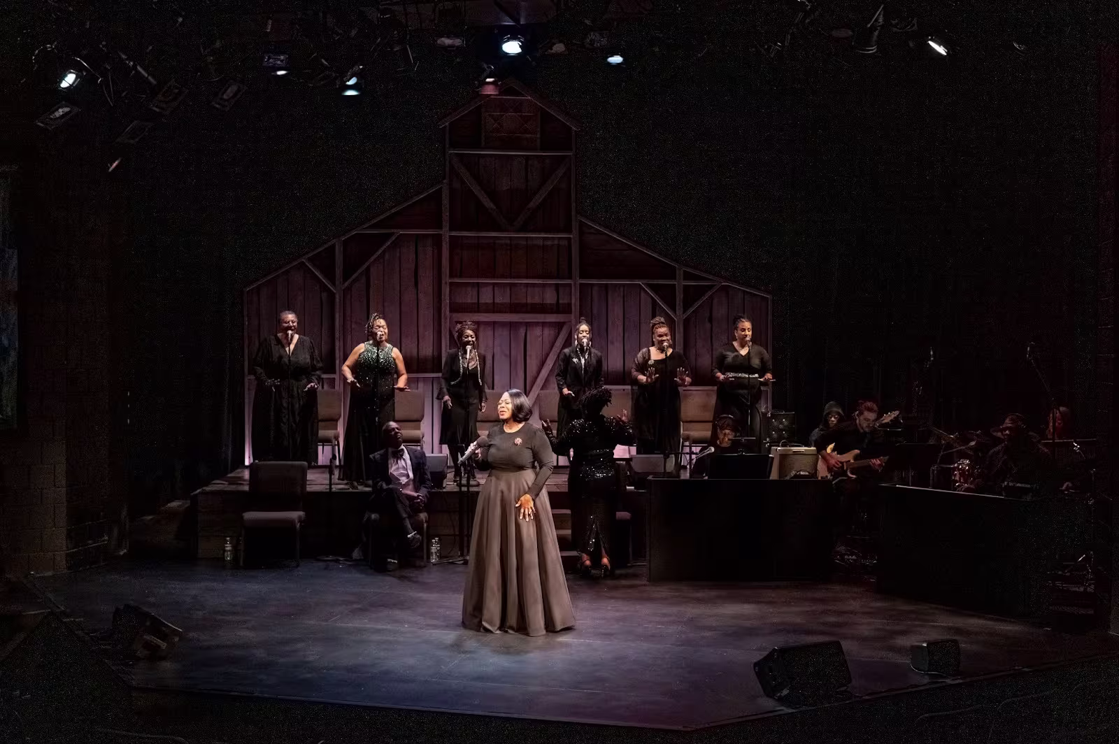 A woman on stage with singers behind her