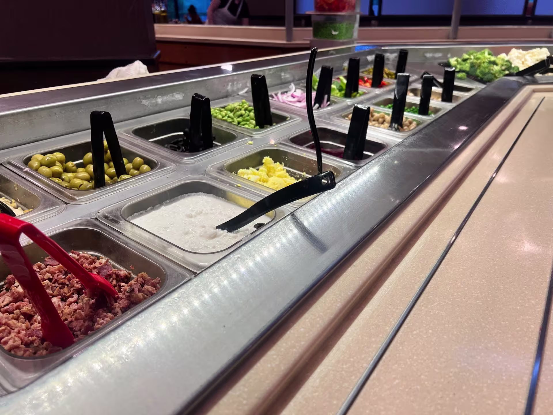 Close-up view of buffet at restaurant, with containers of various salad toppings