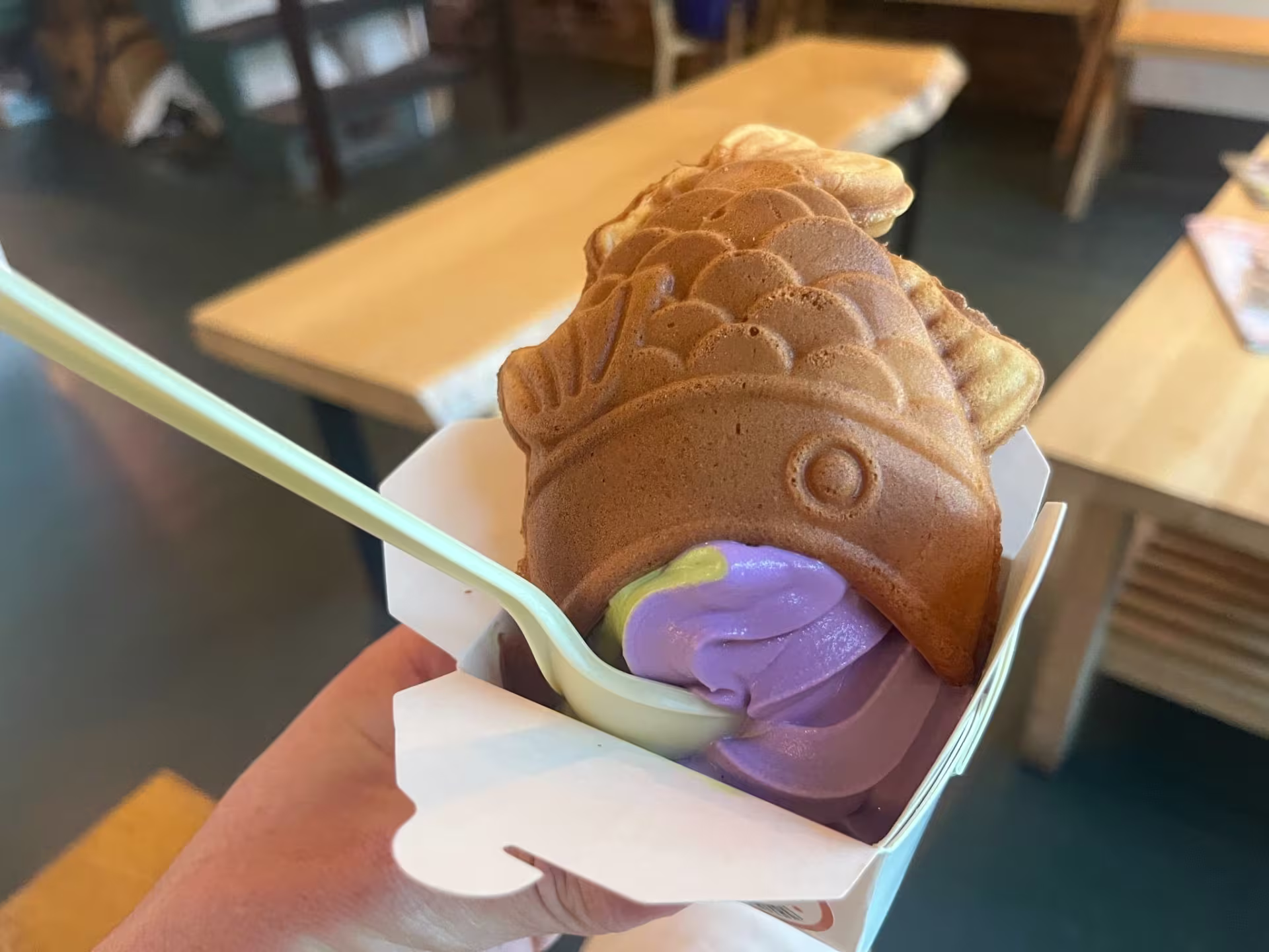 A pastry shaped like a fish with purple ice cream in its mouth