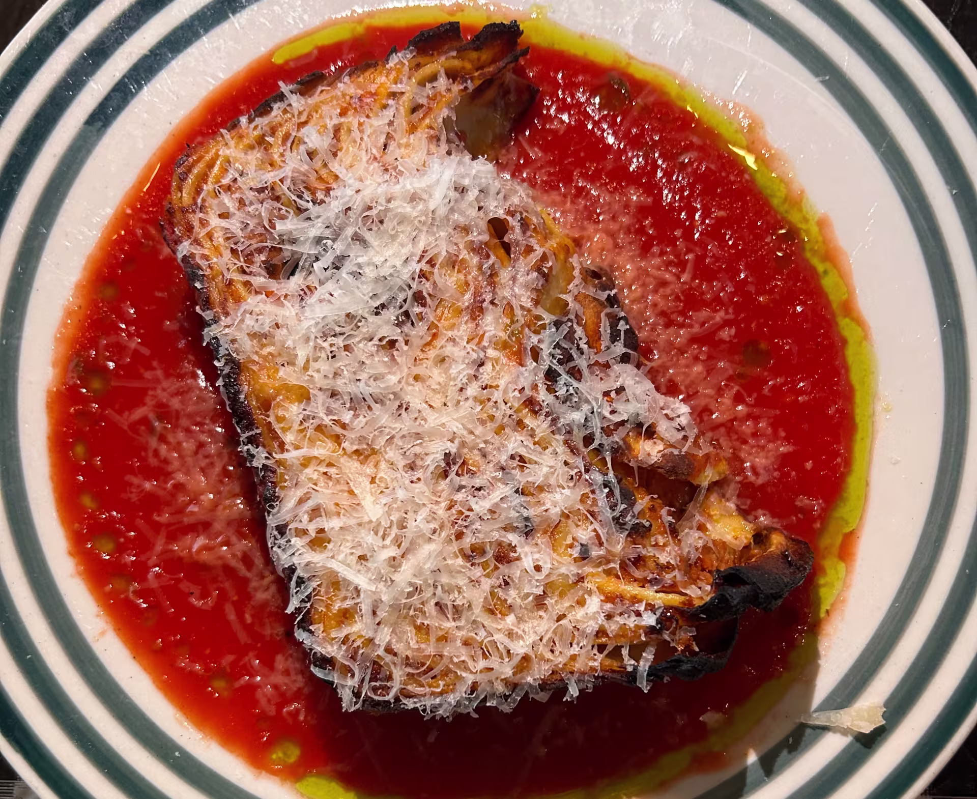 A large piece of lasagna in red sauce with white cheese on top