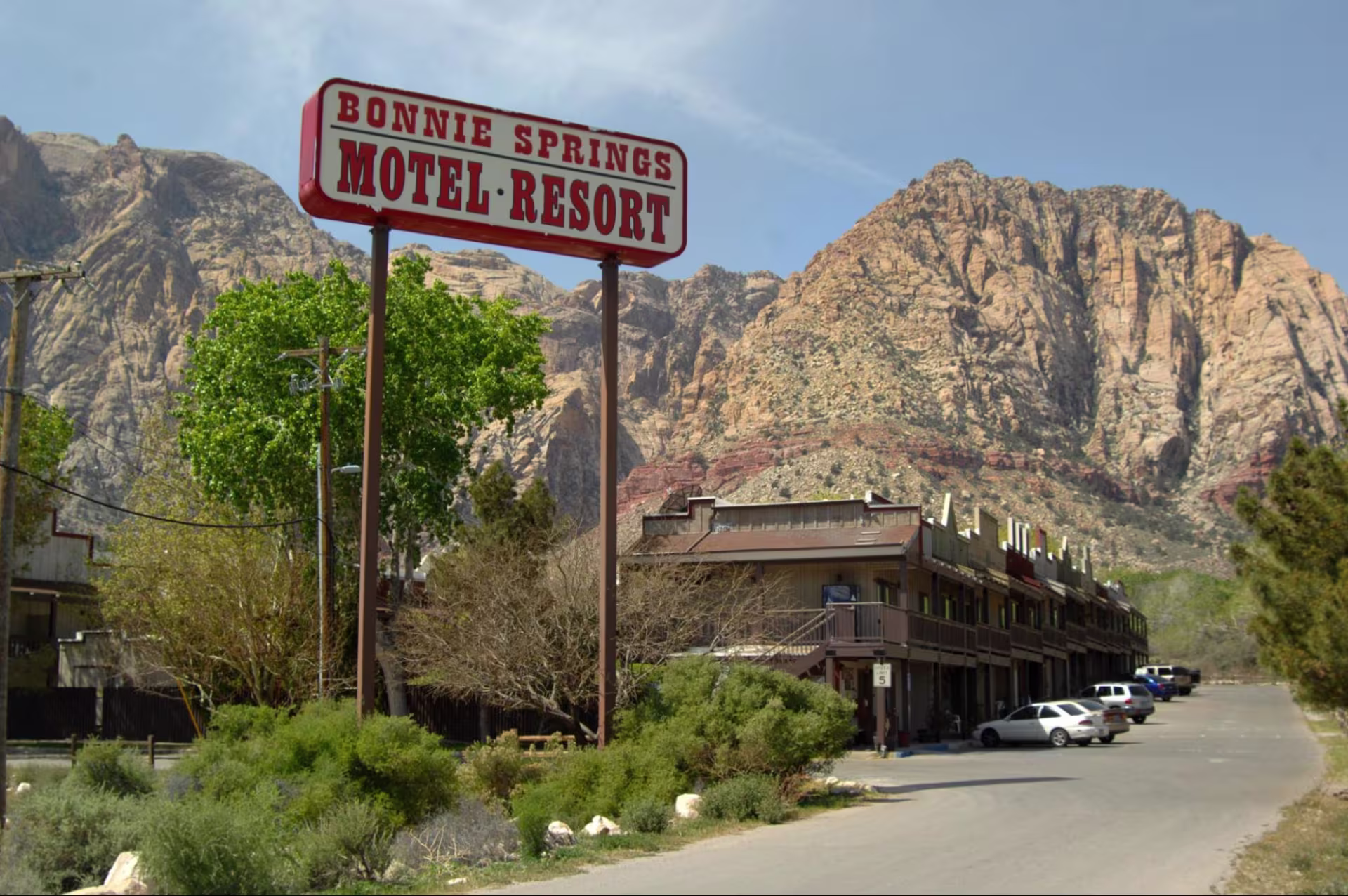 A building up against desert mountains and a sign that reads "Bonnie Springs Motel Resort"