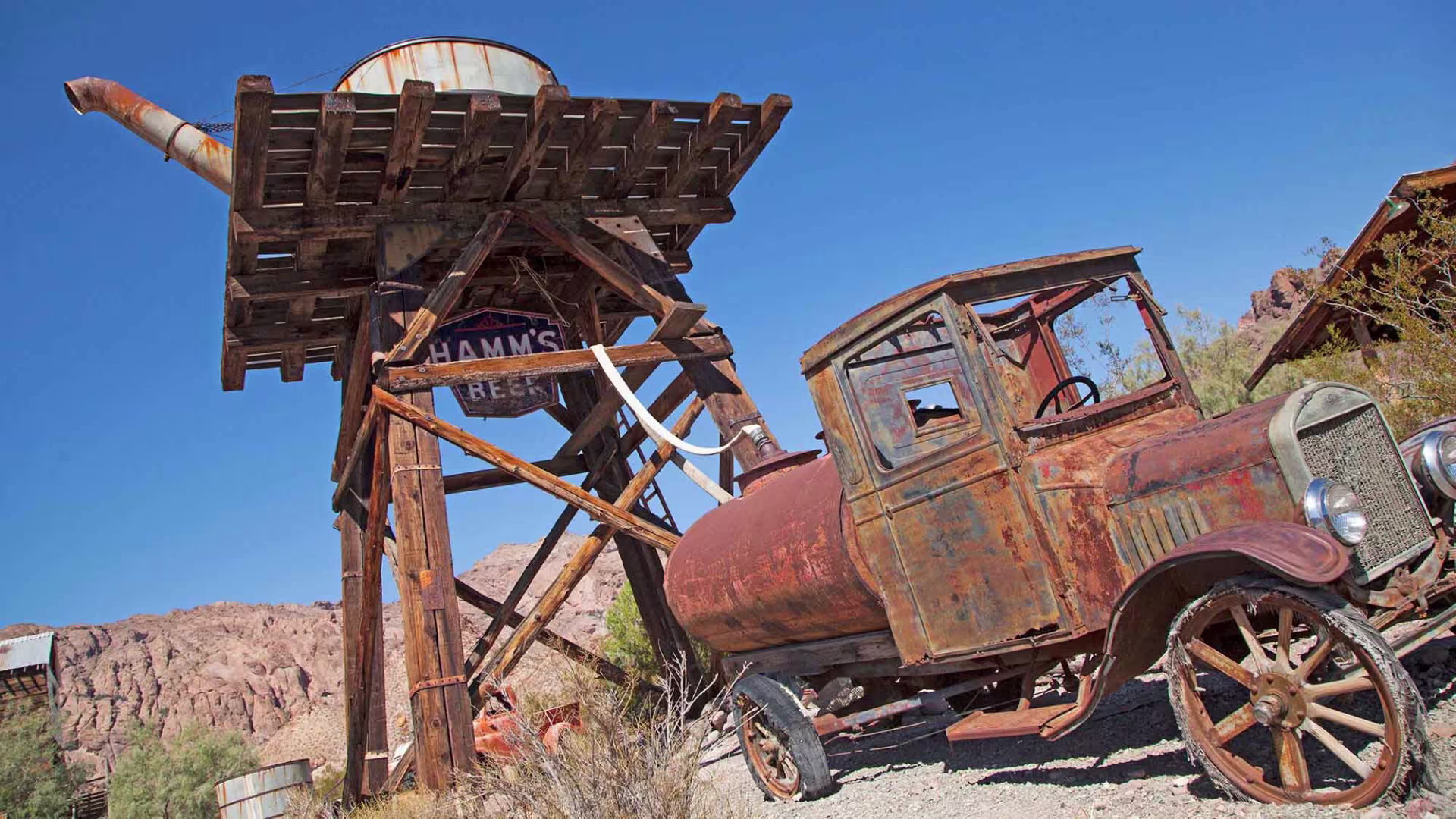 A rusted old truck sits outside an old mine.