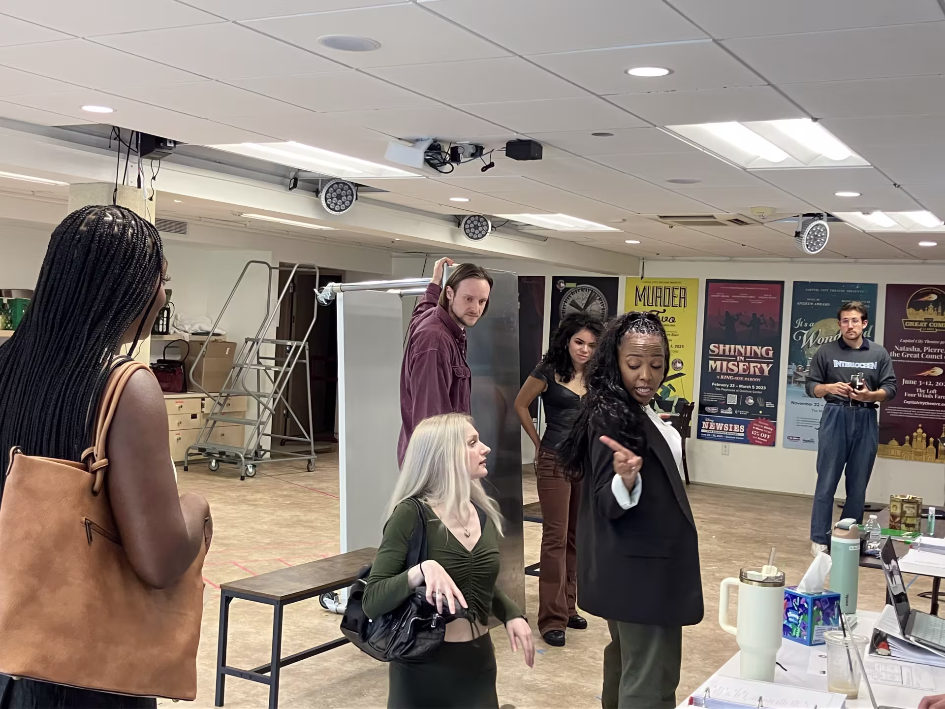 A woman gestures to several other people in a room.