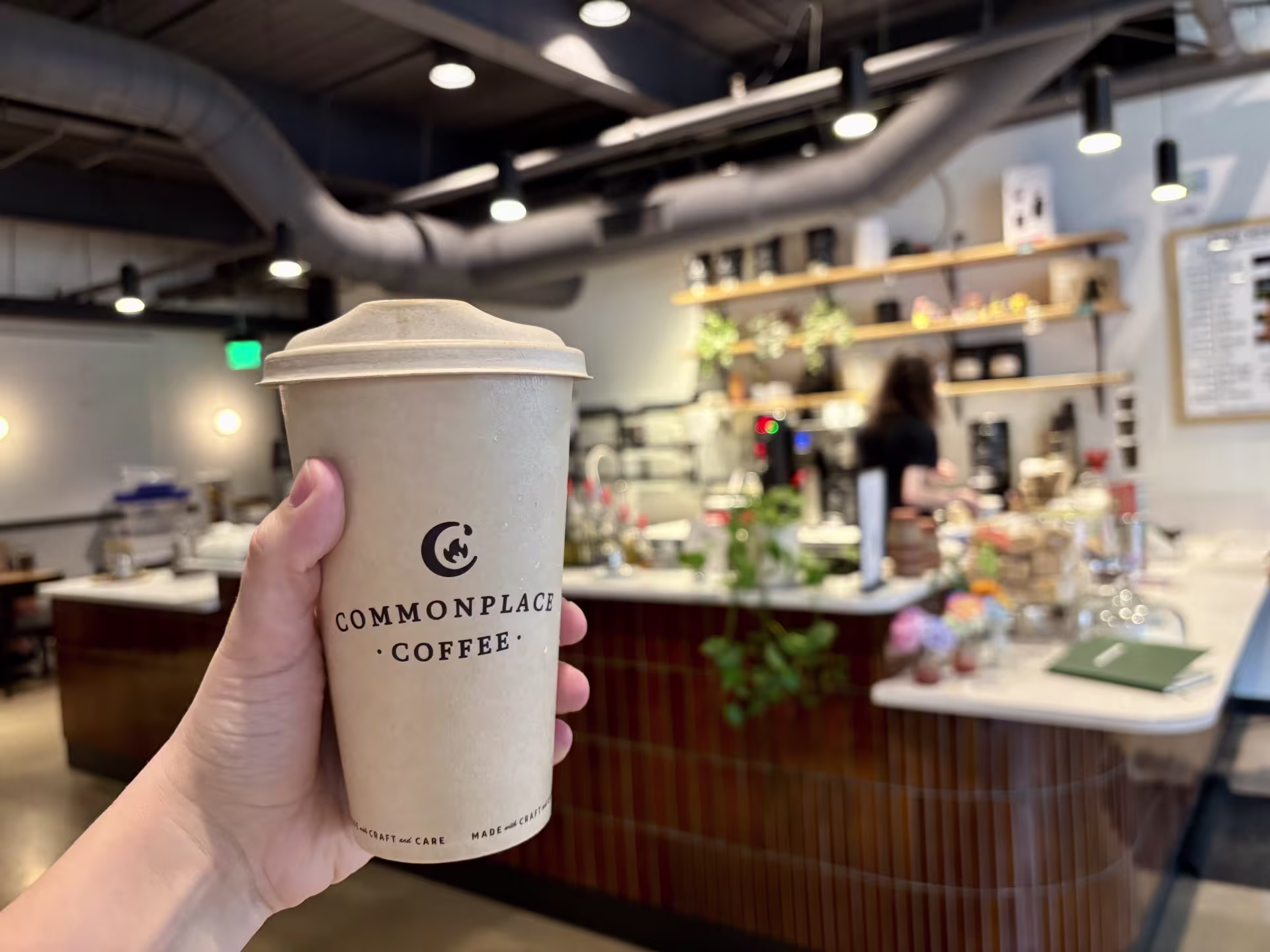 me holding a commonplace coffee mug in front of the barista counter