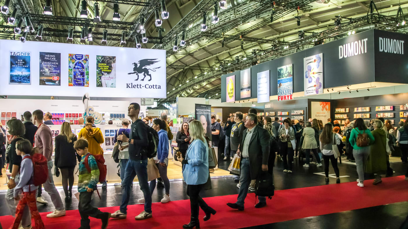 Visitantes circulam entre estandes de editoras alemãs num pavilhão da Feira do Livro de Frankfurt, na edição de 2025