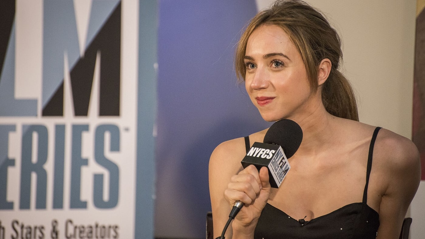 Zoe Kazan segura um microfone e sorri durante evento