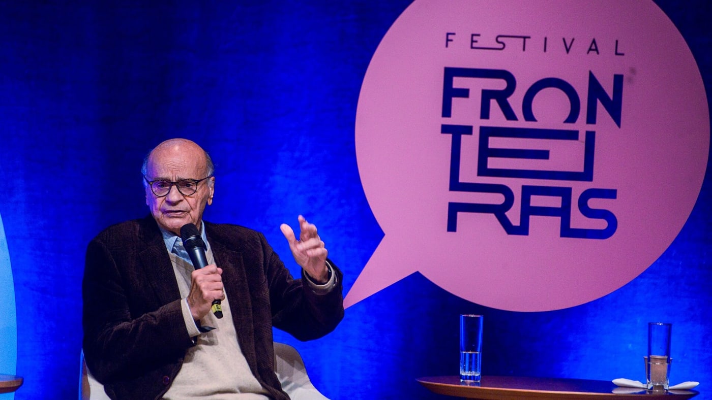 Drauzio Varella fala ao microfone sentado em poltrona durante evento