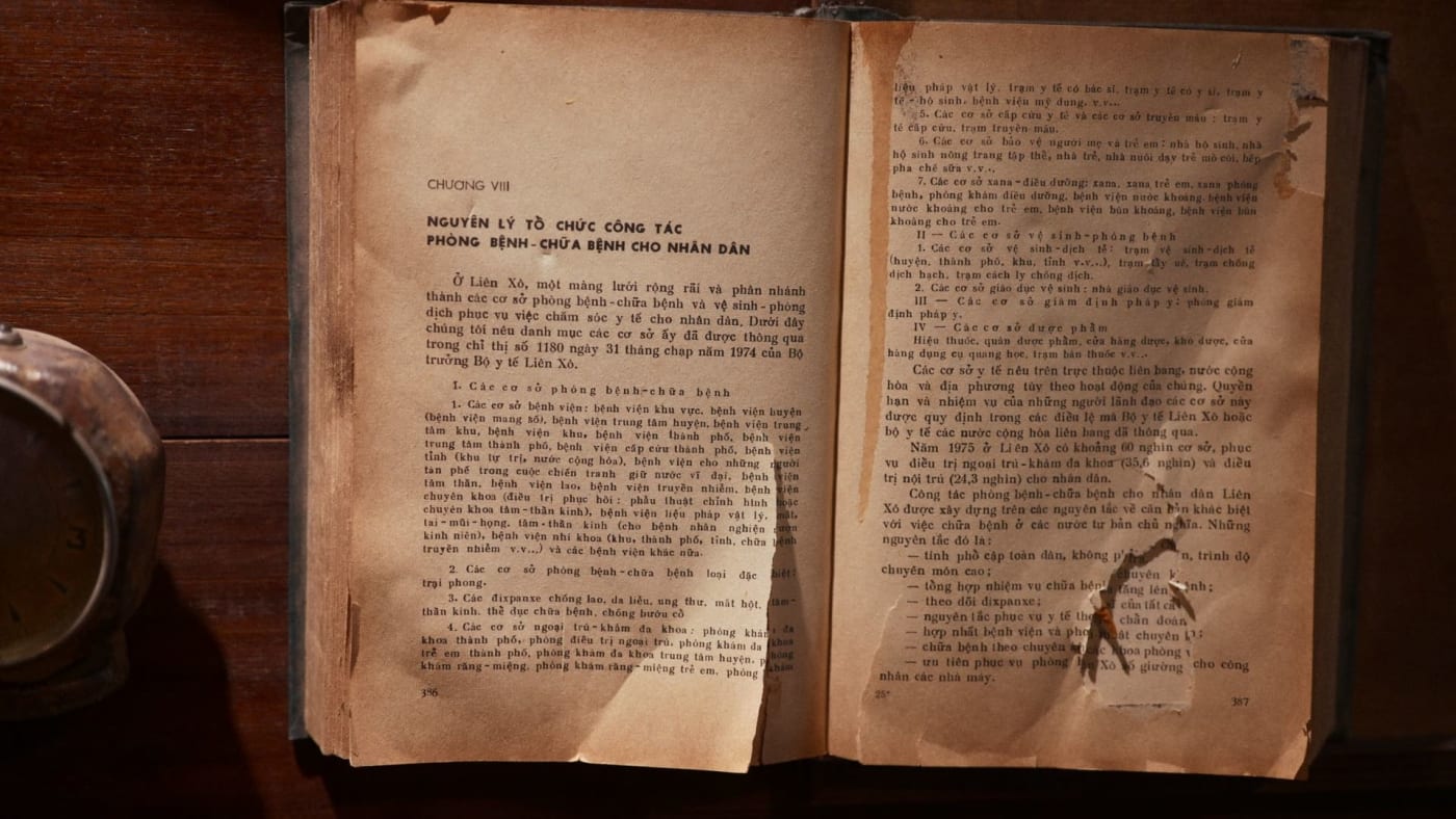 Livro antigo aberto com páginas amareladas sobre superfície de madeira.
