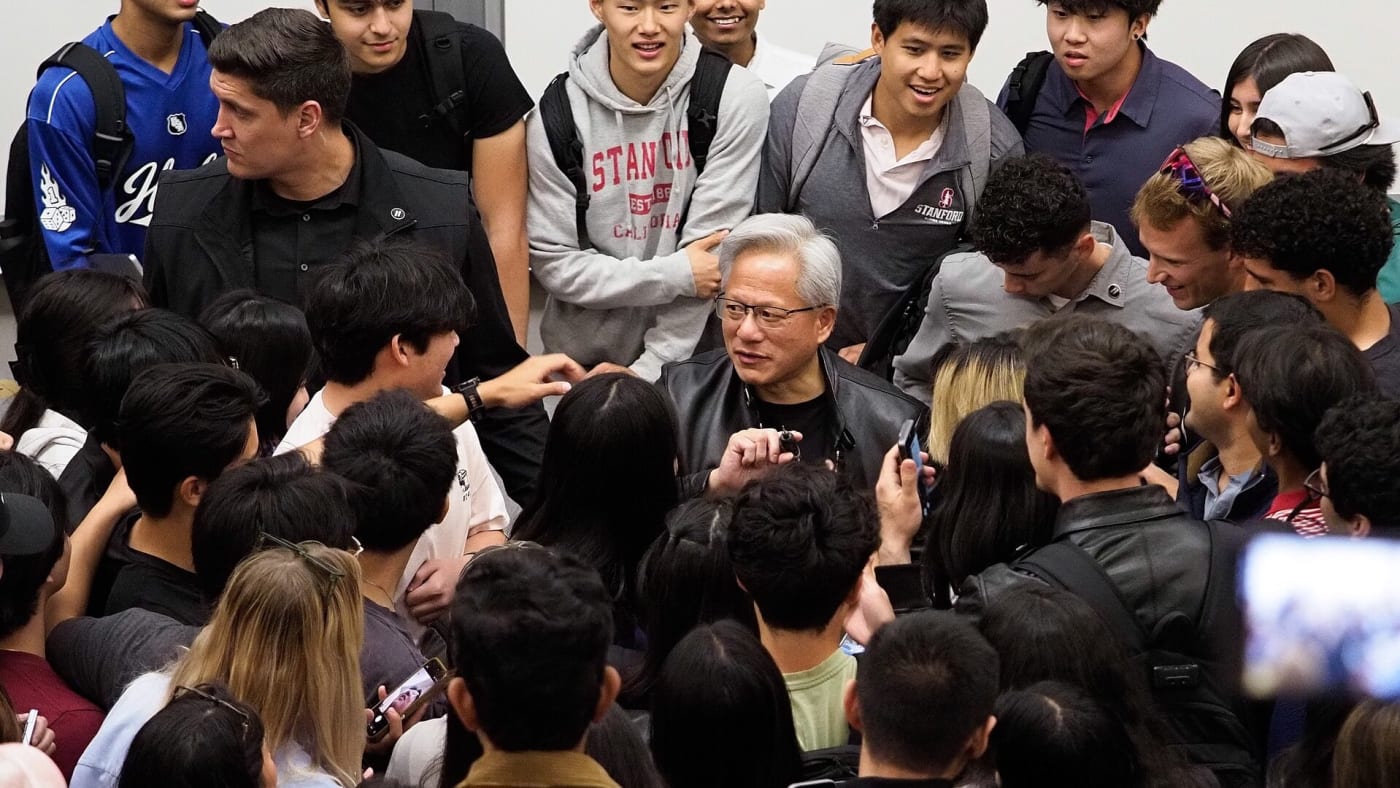 Jensen Huang conversa cercado por estudantes em evento universitário
