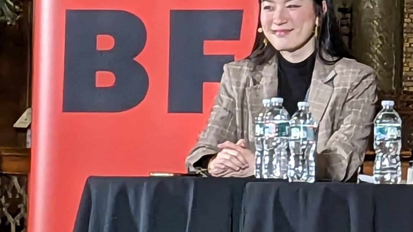 Chloe Gong sorri sentada a uma mesa durante o Boston Book Festival.
