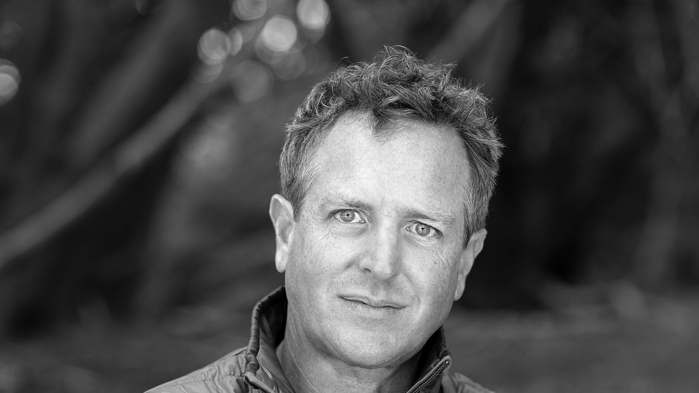 Retrato em preto e branco do escritor Hugh Howey com os braços cruzados.