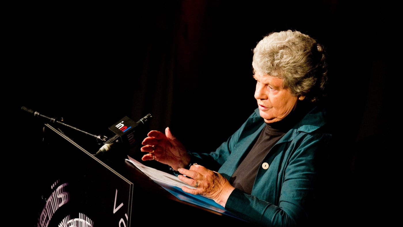A. S. Byatt discursa em um púlpito durante evento