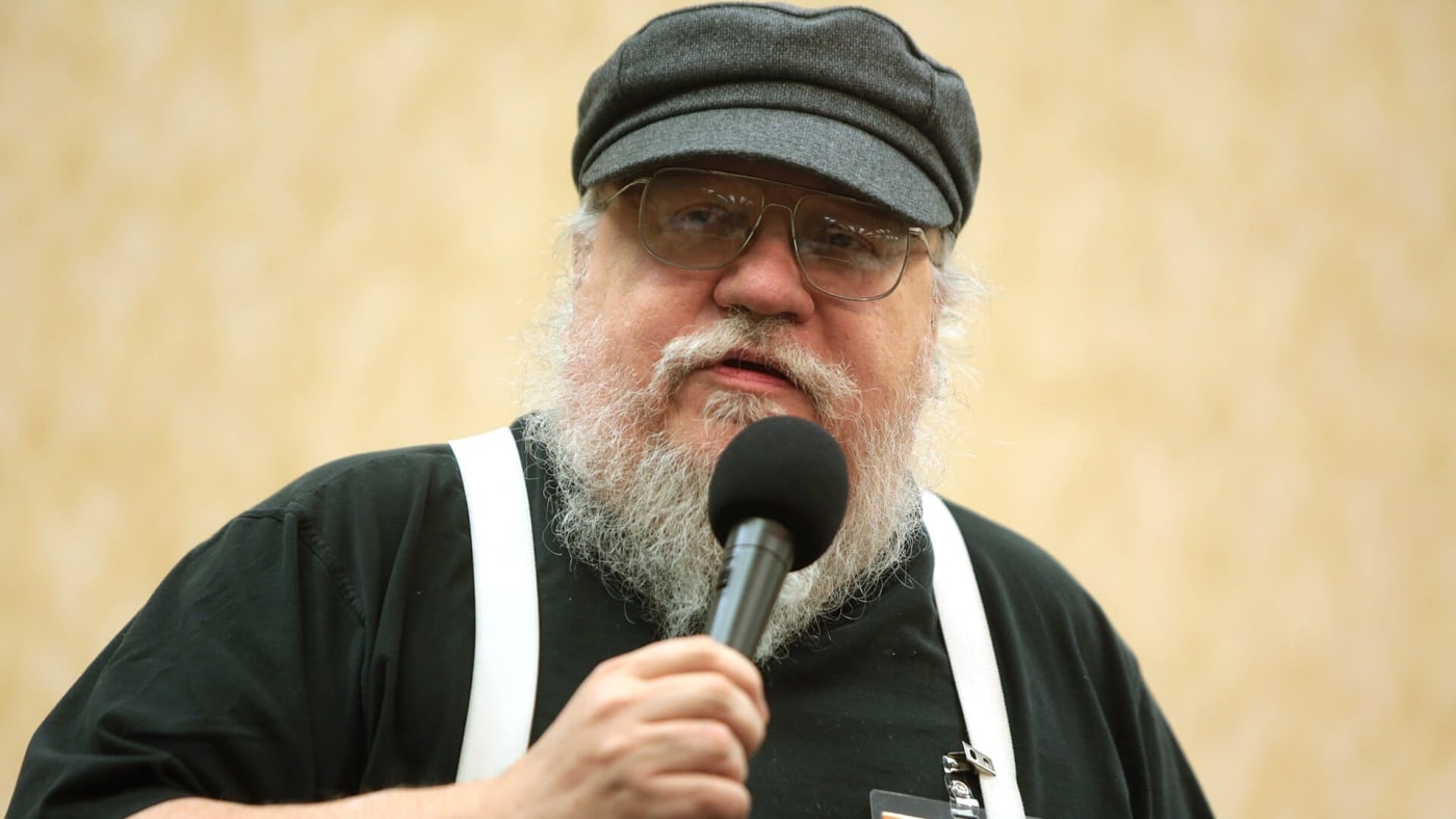 George R. R. Martin segura um microfone ao falar durante um evento