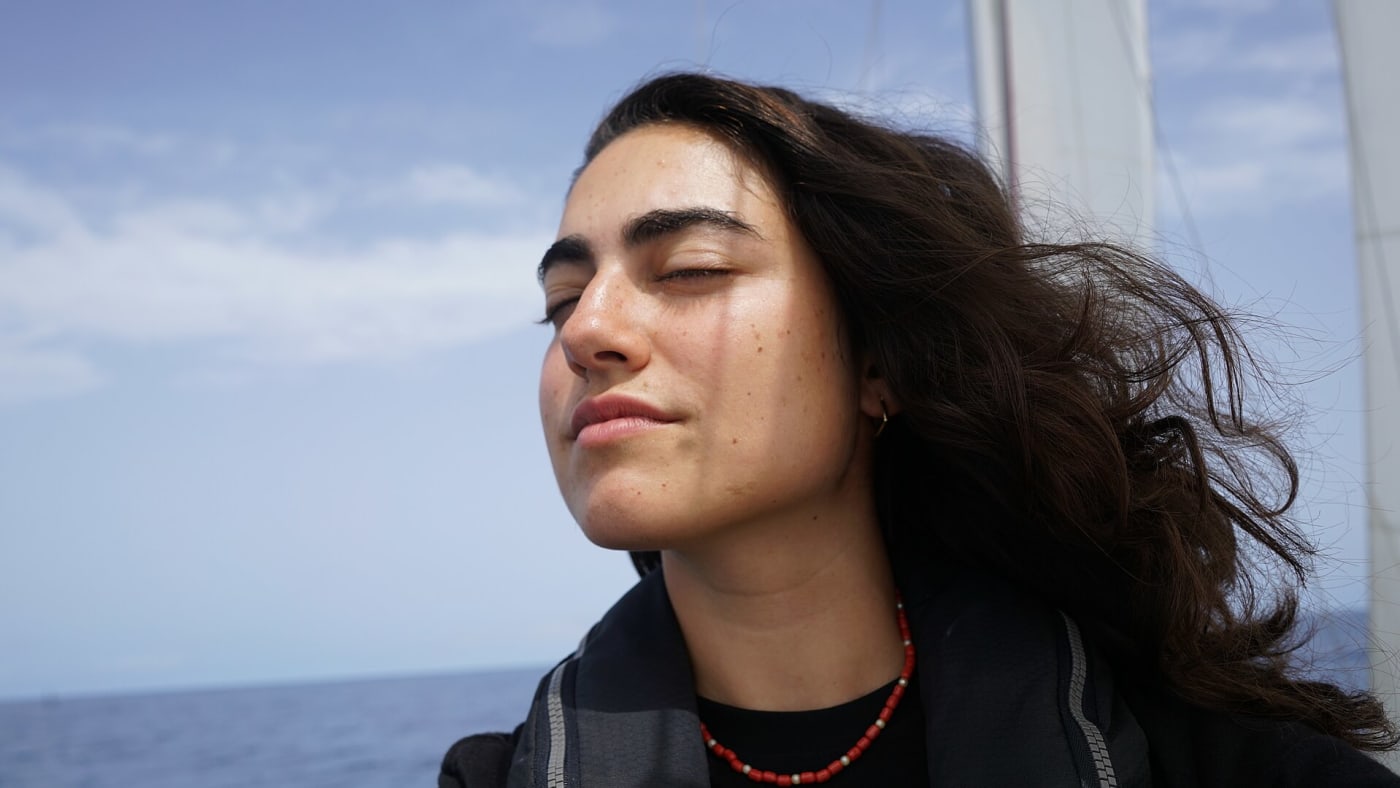 Tamara Klink de olhos fechados com vento no cabelo a bordo de um veleiro